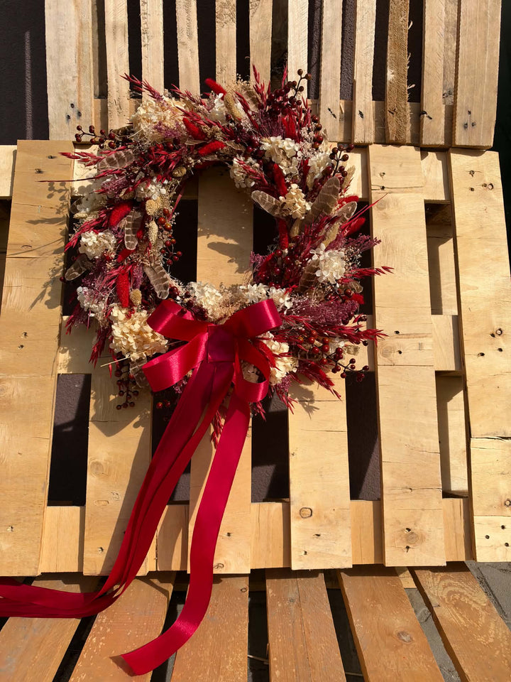 Measuring approximately 45 cm in diameter, this wreath creates a beautiful focal point on an interior door or wall. Imagine it above a wooden console, bringing colour to the everyday ritual of coming home. Its red and cream palette pairs beautifully with warm wood, woven textiles and simple seasonal decorations. 