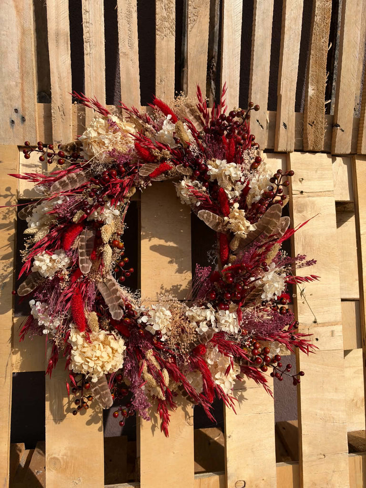 Measuring approximately 45 cm in diameter, this wreath creates a beautiful focal point on an interior door or wall. Imagine it above a wooden console, bringing colour to the everyday ritual of coming home. Its red and cream palette pairs beautifully with warm wood, woven textiles and simple seasonal decorations. 