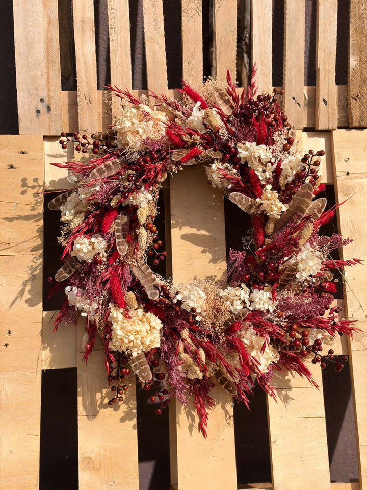 Measuring approximately 45 cm in diameter, this wreath creates a beautiful focal point on an interior door or wall. Imagine it above a wooden console, bringing colour to the everyday ritual of coming home. Its red and cream palette pairs beautifully with warm wood, woven textiles and simple seasonal decorations.