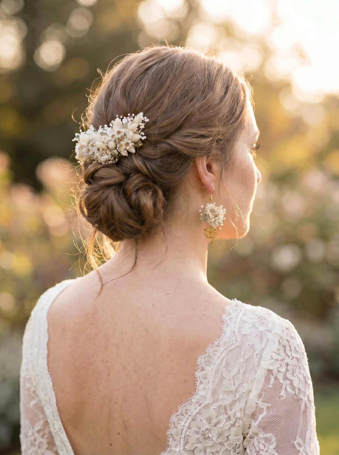 Bride with styled hair and floral hairpiece with elegant bridal earrings in an outdoor setting