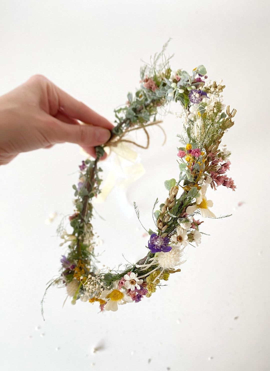 Hand holding a floral wreath on a white background