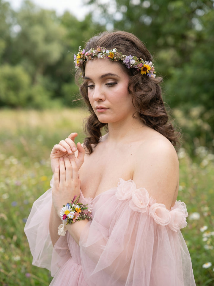 Woman in a pink dress with floral accessories in a natural setting
