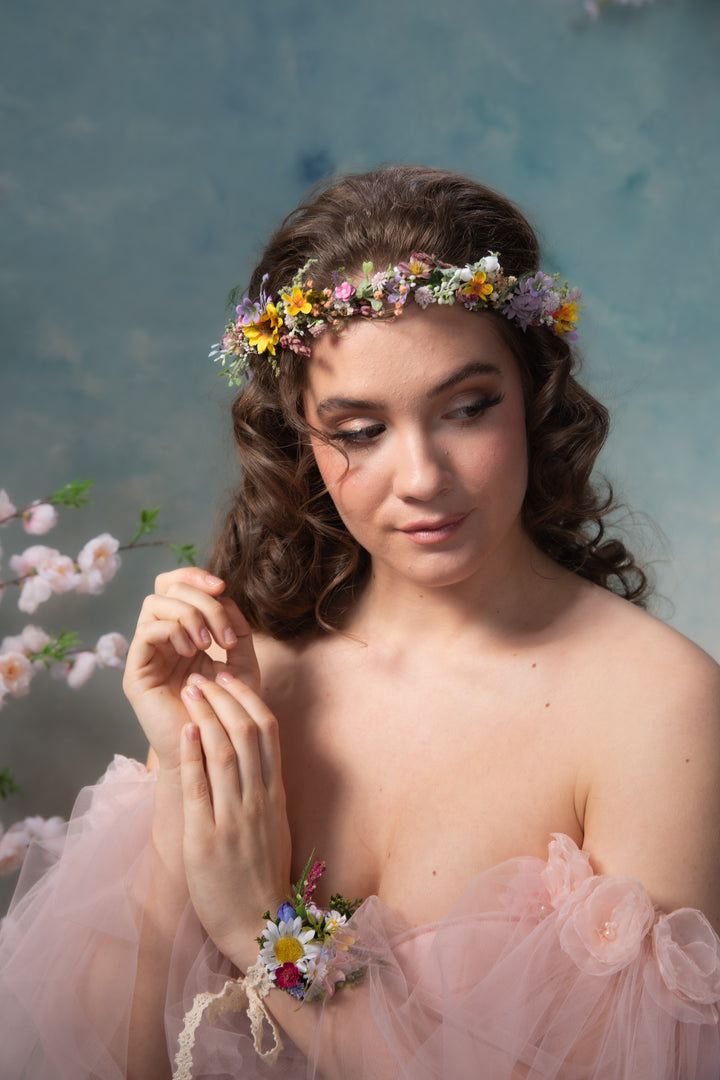 Woman in a pink dress with floral wildflowers crown against a blue background
