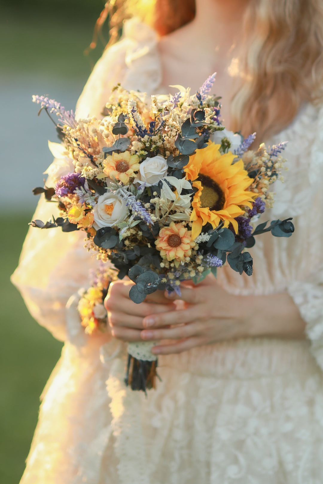 Person holding a bouquet of sunflowers and other flowers outdoors