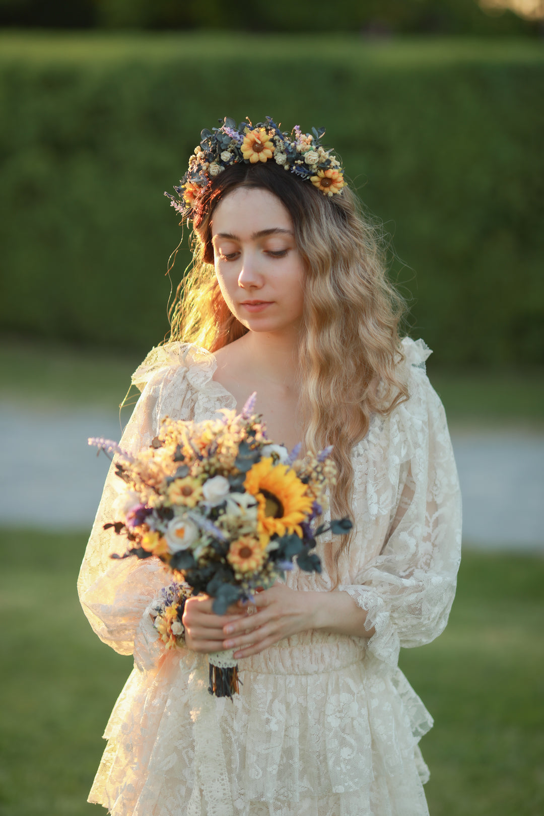 Woman in a floral lace dress holding a bouquet of flowers outdoors, with headband in the hair 