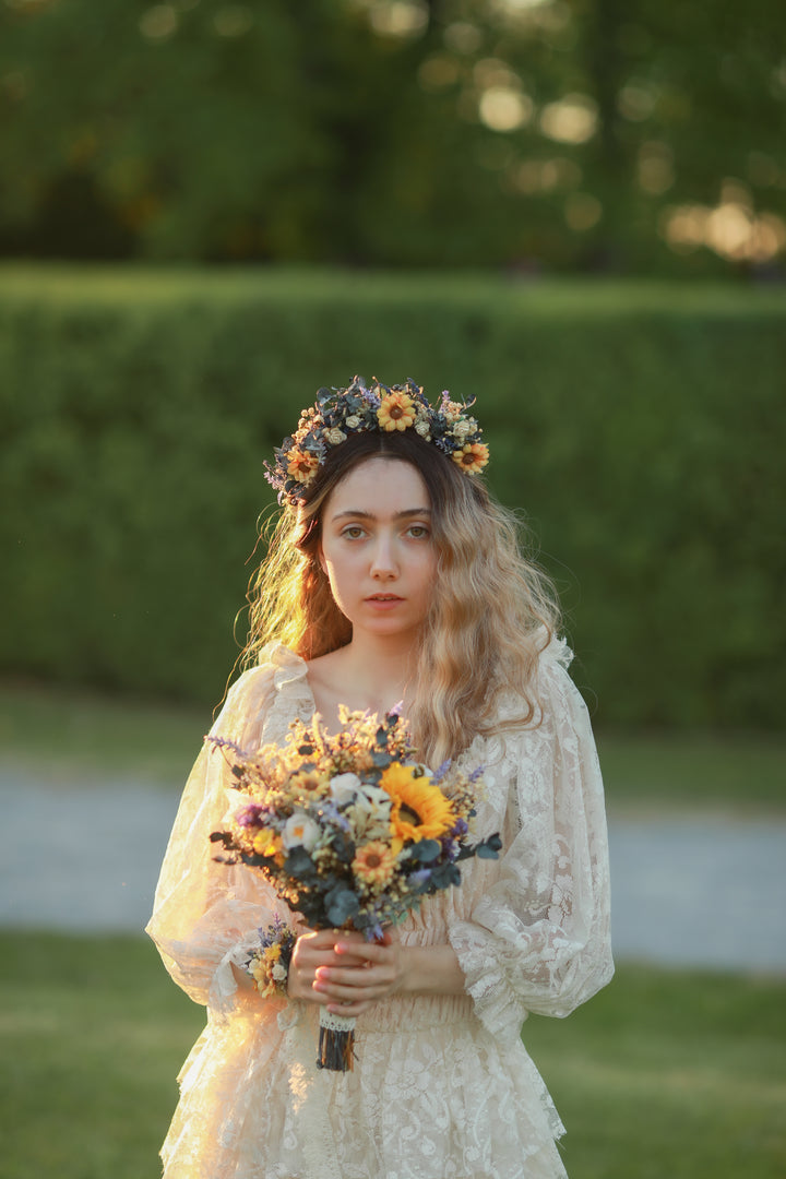 Woman in a white dress with a floral headpiece and bouquet standing outdoors.