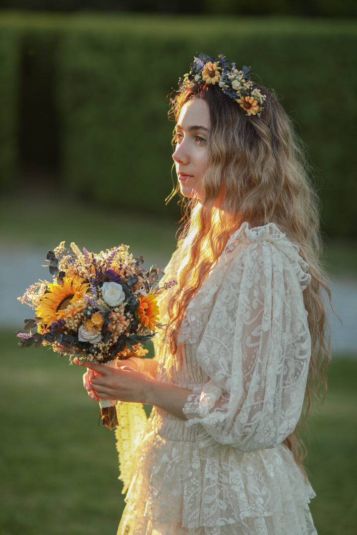 Woman in a lace dress holding a bouquet of flowers with a blurred green background