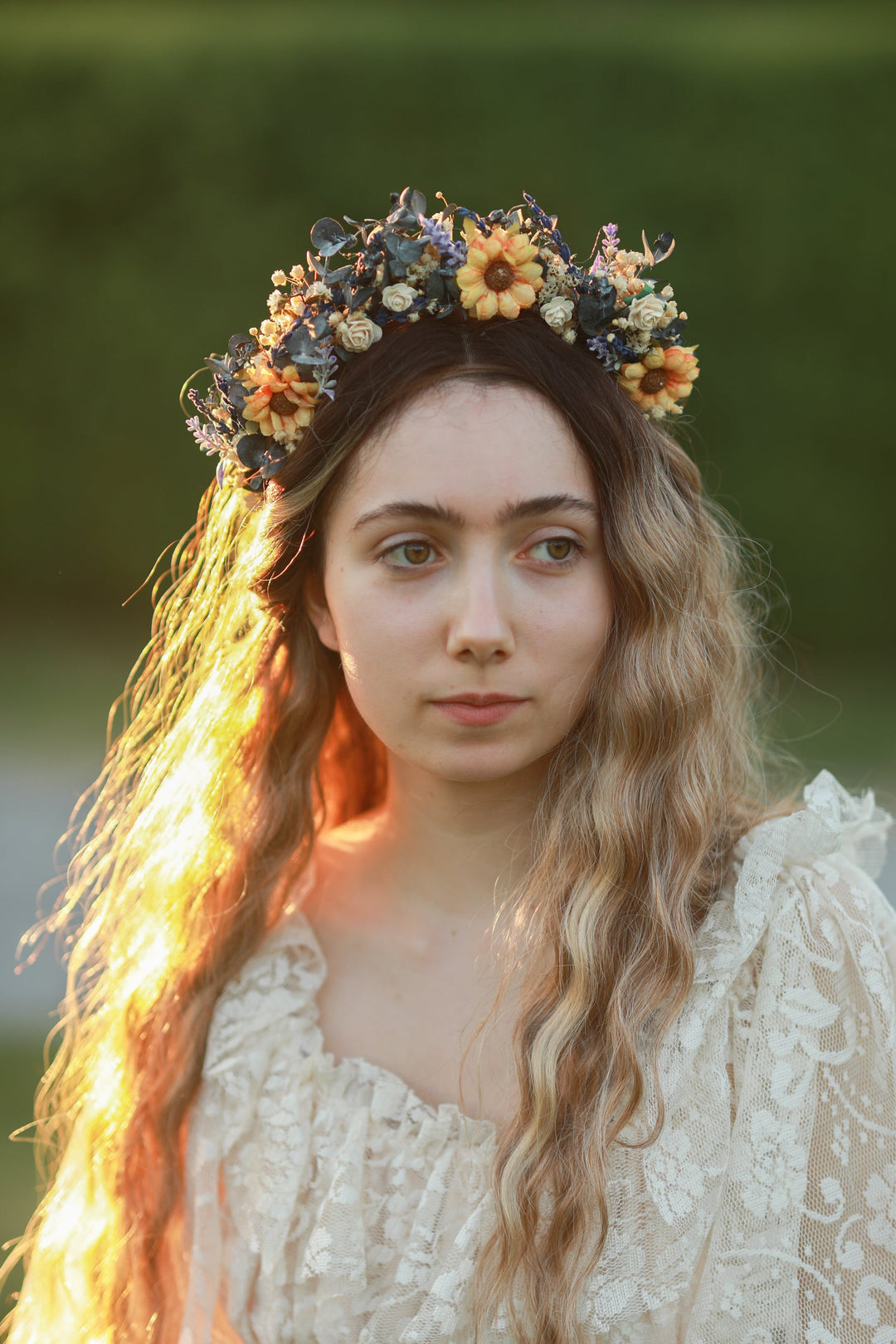 Woman wearing a floral sunflower crown with a blurred green background