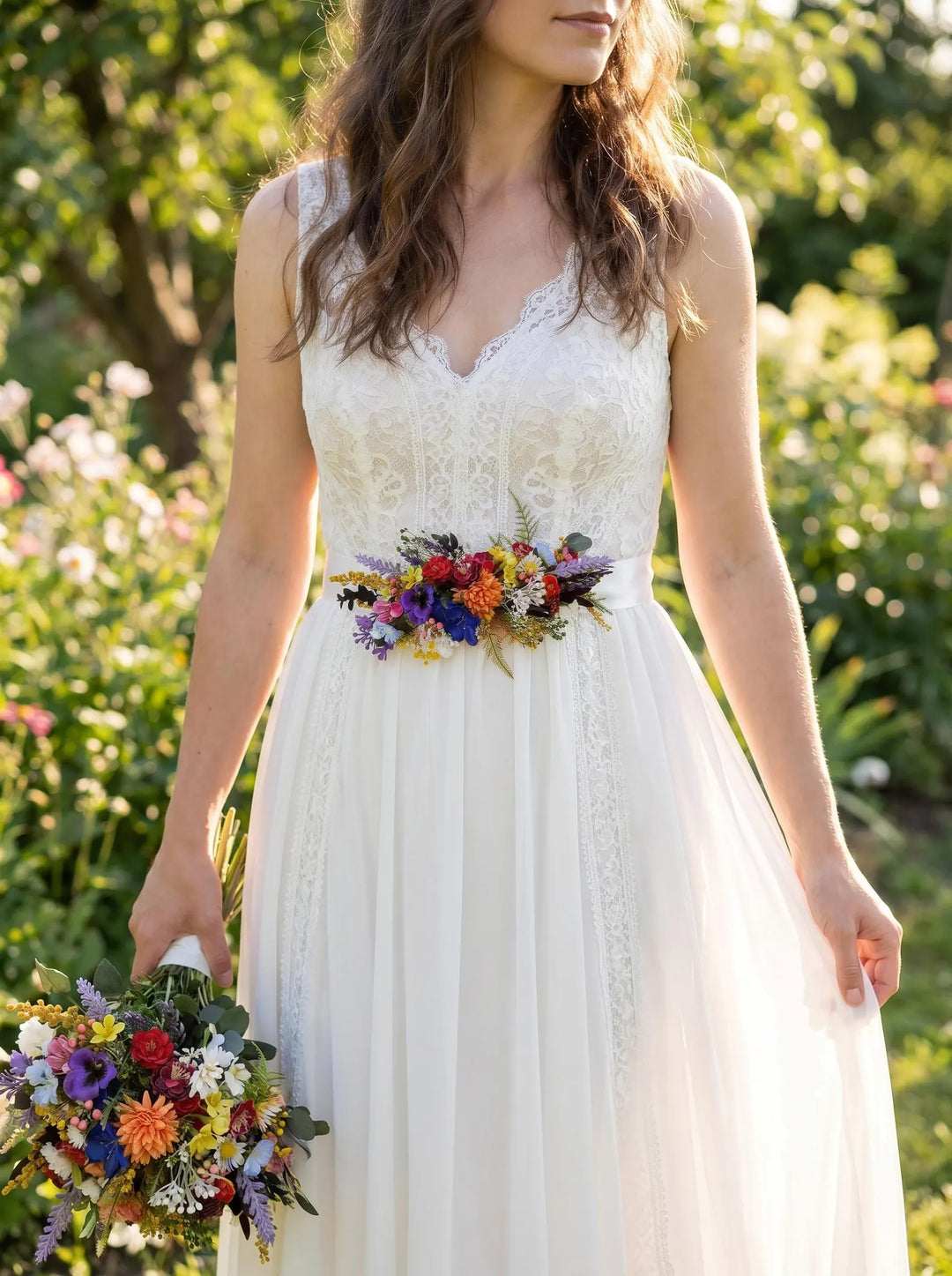 Woman in a white dress with colorful bridal belt holding a colorful bouquet in a garden setting