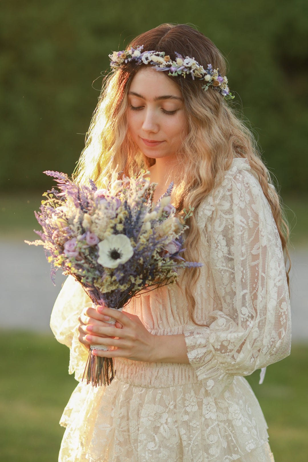 Woman in a lace dress holding a bouquet of flowers outdoors