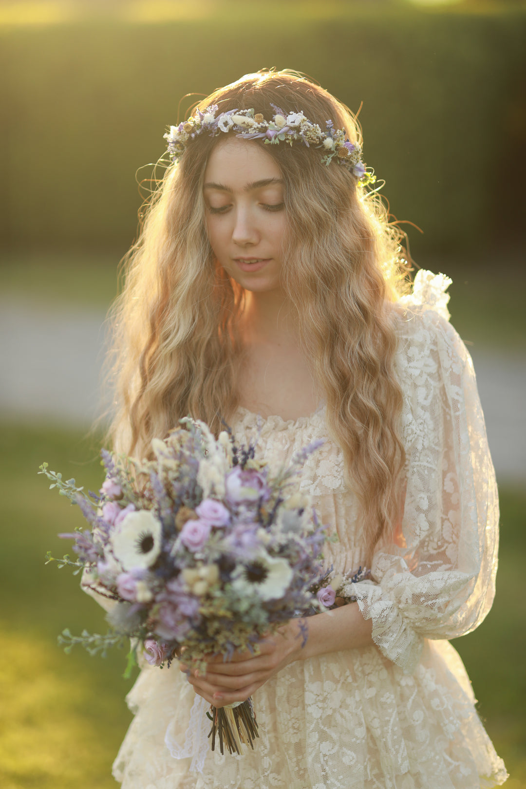 Woman in a white dress holding a bouquet of flowers with a blurred natural background