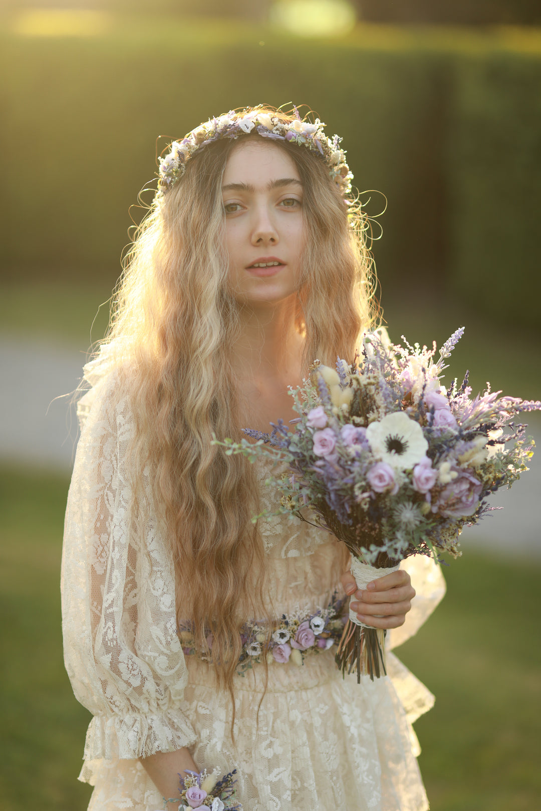 Woman in a lace dress holding a bouquet of flowers outdoors