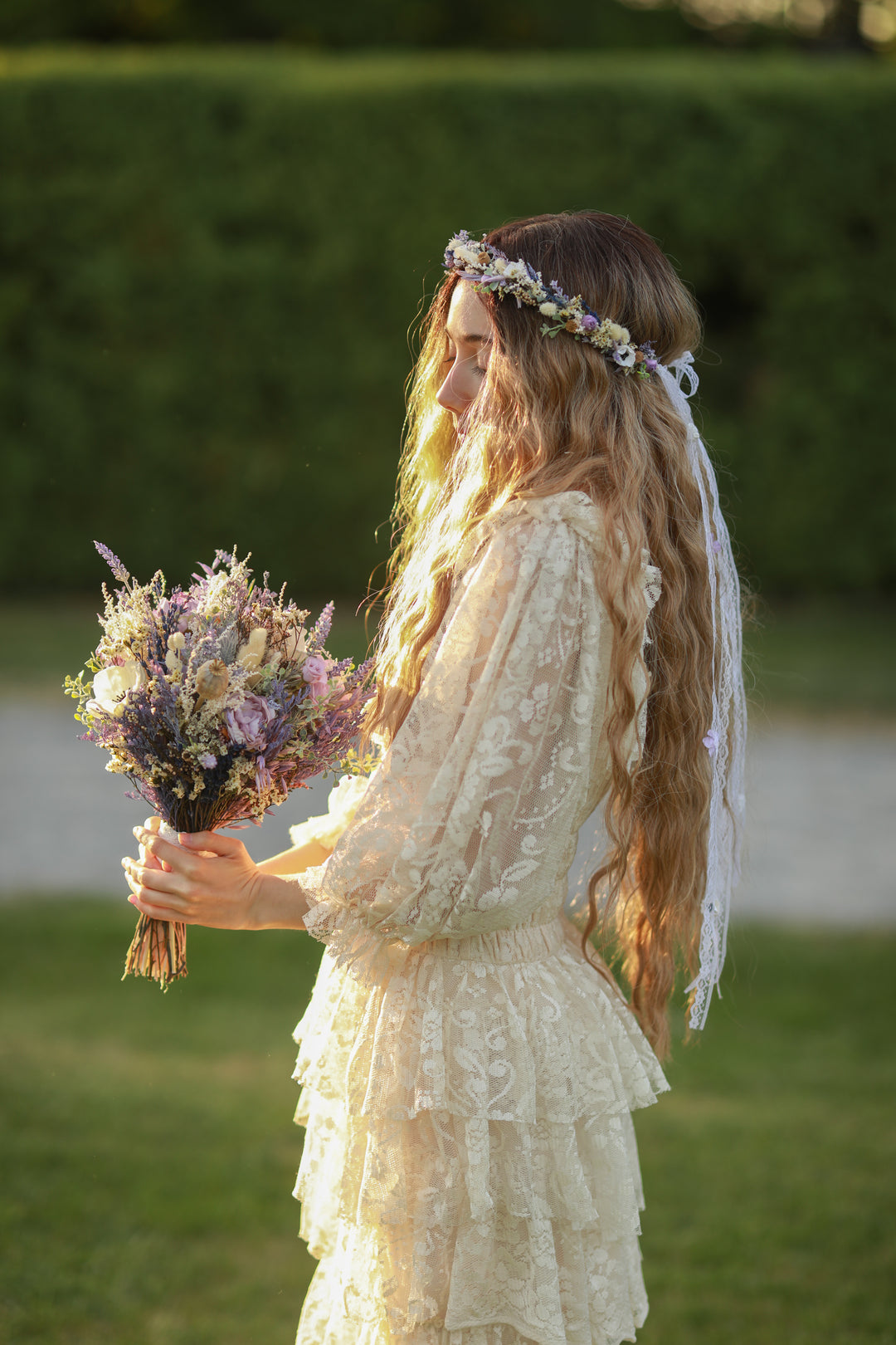 Woman in a lace dress holding a bouquet of flowers with a blurred green background