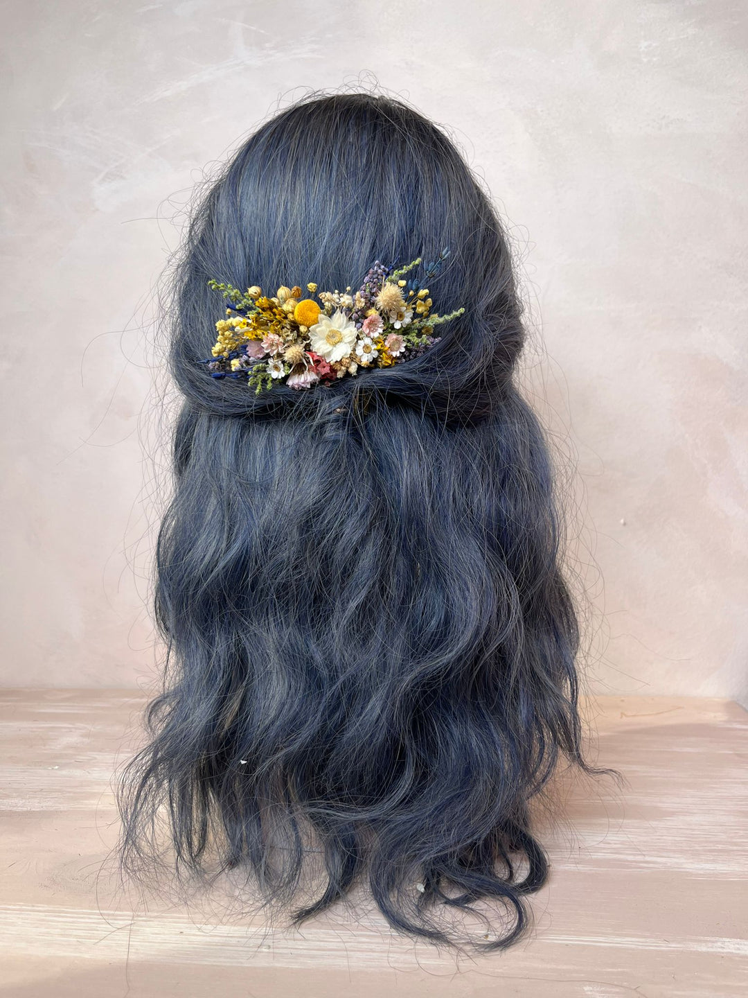 Floral hair accessory in blue hair with a neutral background