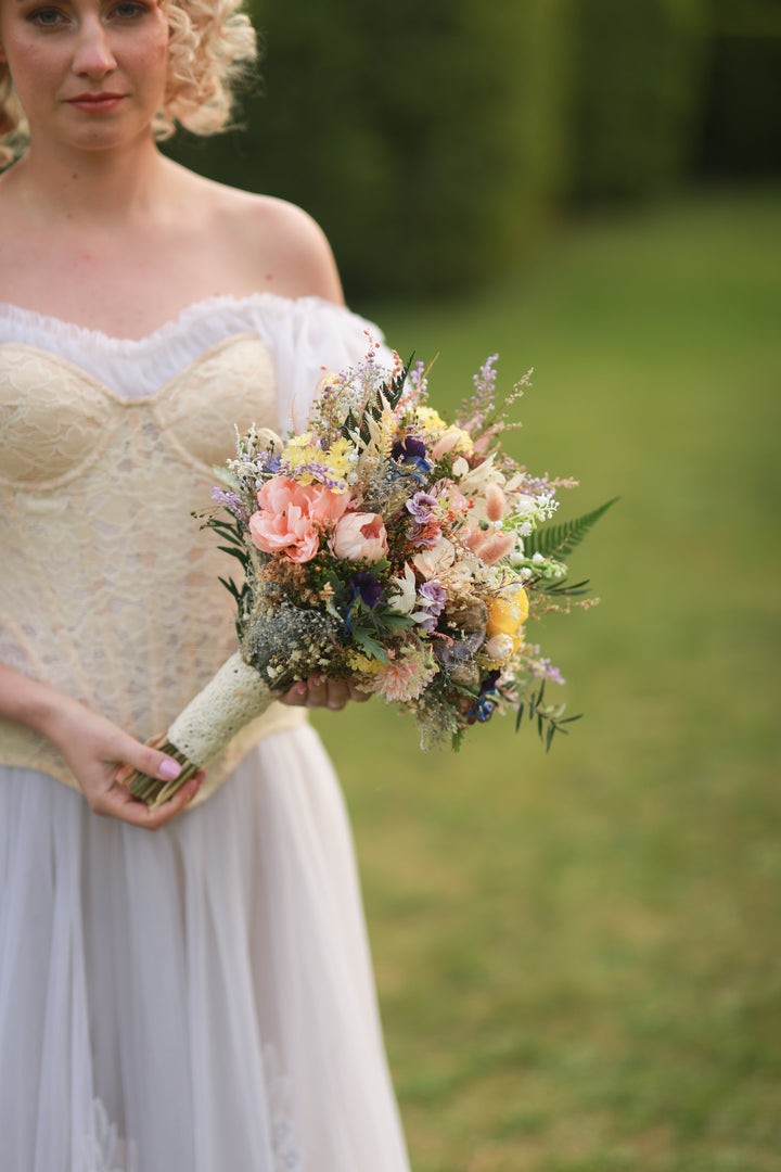 Woman holding a bouquet of flowers outdoors on a grassy background