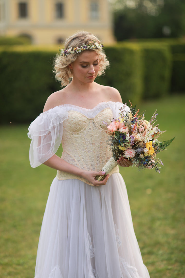 Woman in a white wedding dress holding a bouquet in an outdoor setting