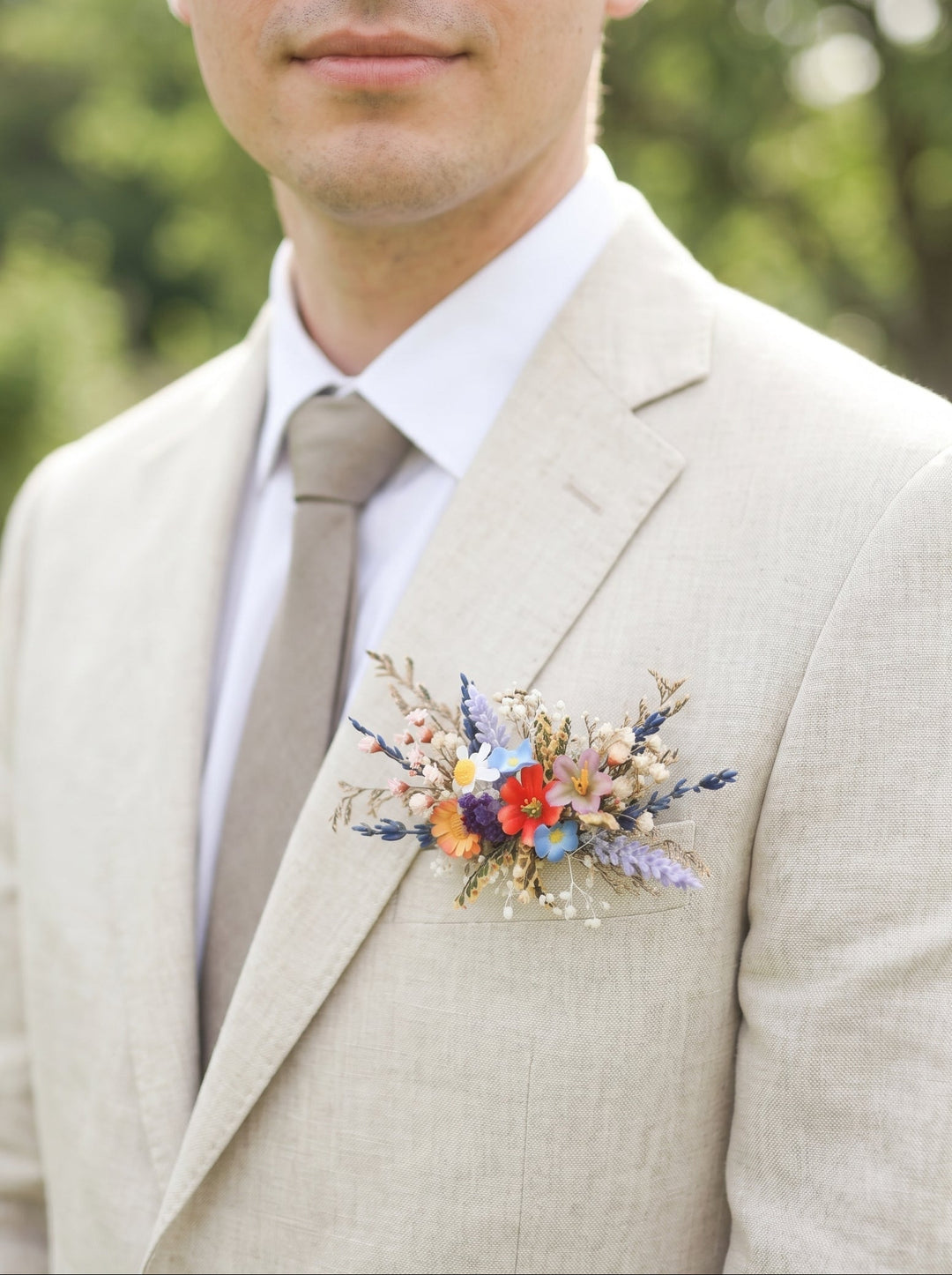 Man wearing a light gray suit with a colorful floral boutonniere.