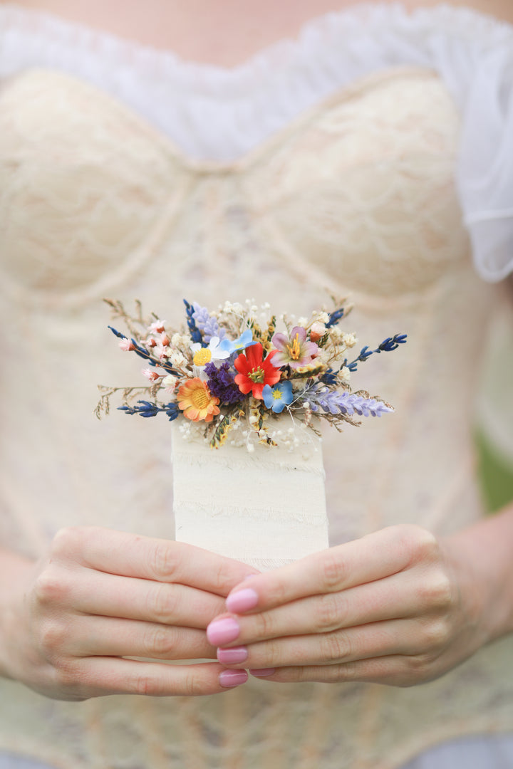 Colorful floral boutonniere on a person wearing a white lace garment.