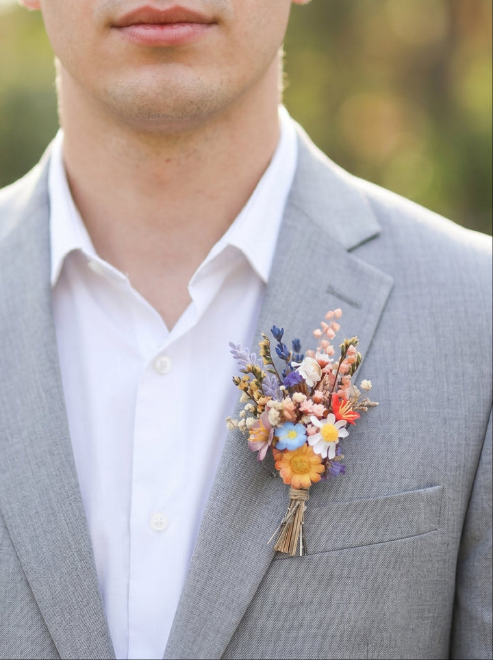 Man wearing a gray suit with a colorful floral boutonniere outdoors